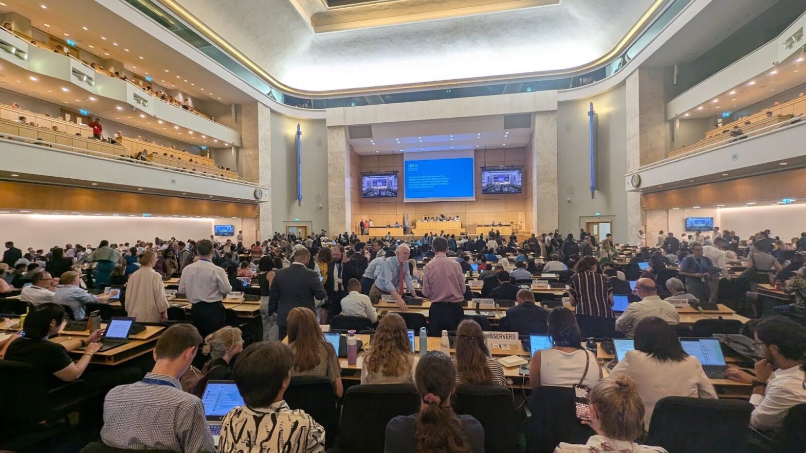 Delegates gather for an explosive plenary with frenzied huddles across the room digesting the new Chairs Text. Photo: Sam Winton.