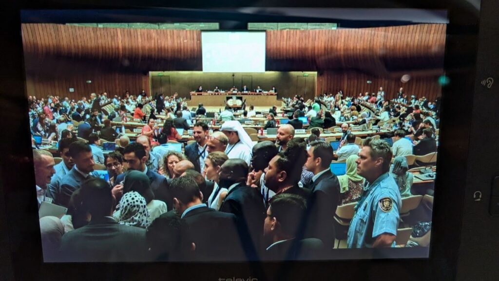 Photo of delegates engaged in a tense huddle at INC 5.2 of the Global Plastics Treaty negotiations